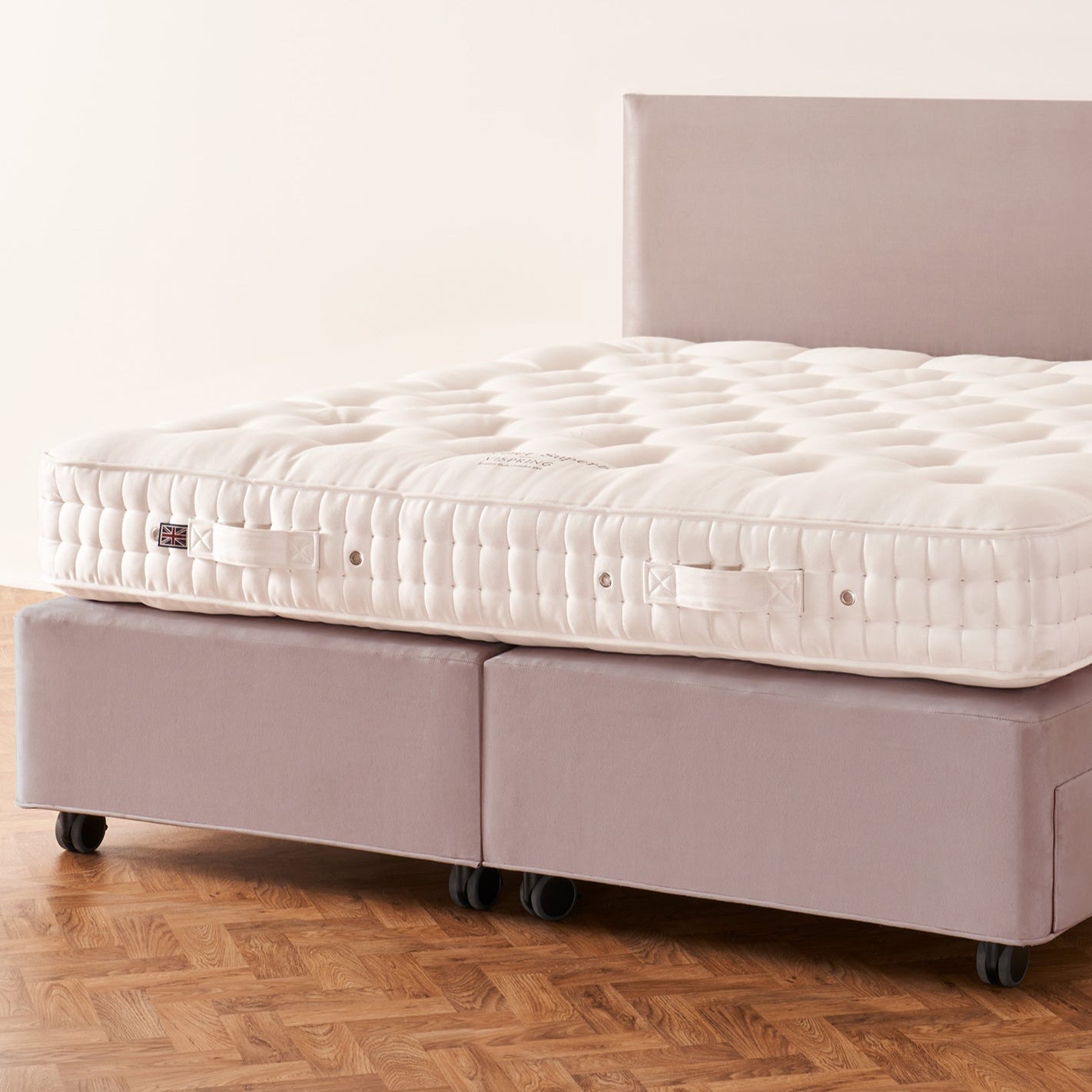 Mattress on a bed frame with a wooden floor and white wall background