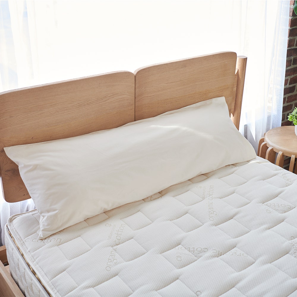 Room view Naturepedic Non-Toxic Body Pillow laying on top of mattress