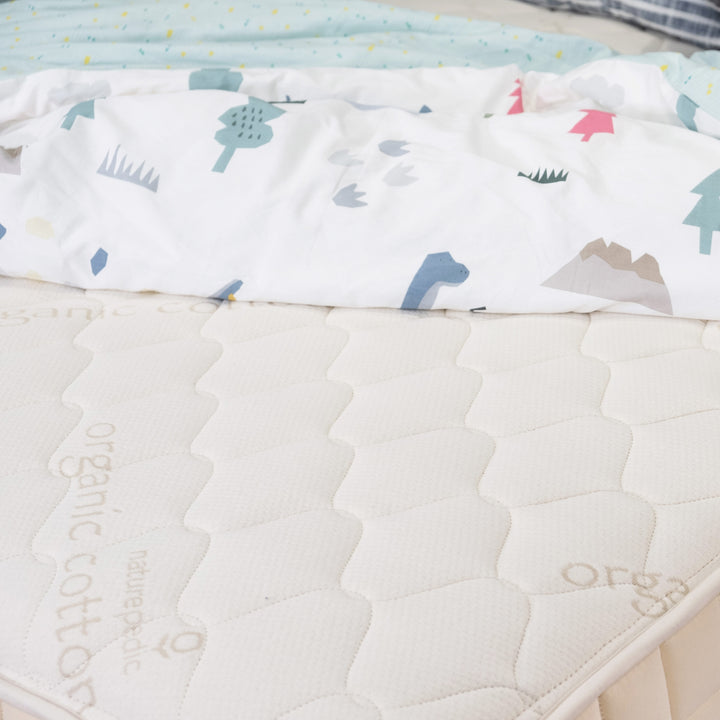 Close up Naturepedic Verse Mattress with blanket dressed on it 
